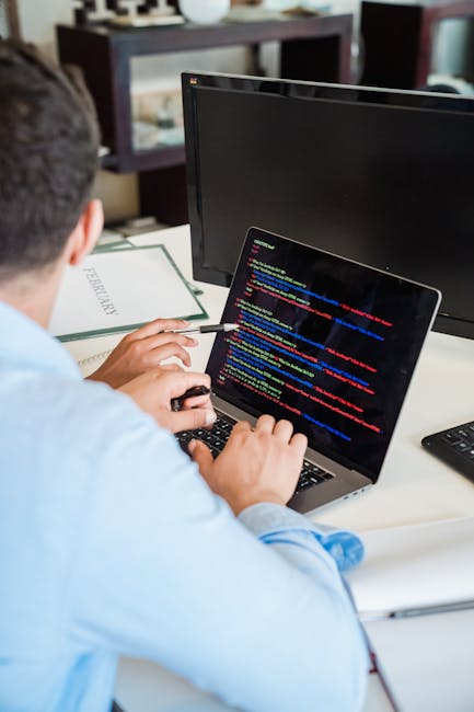 Photograph of a computer screen displaying a close-up of colorful programming code on a dark background. The code includes various syntax elements such as functions, variables, and conditional stateme